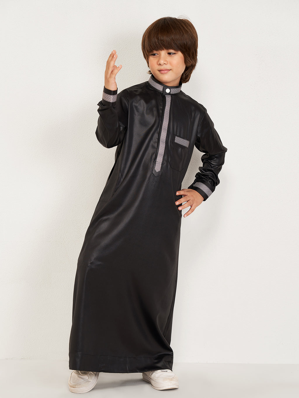 Child wearing a black traditional outfit with gray accents on a white background