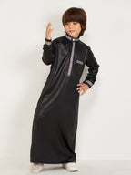 Child wearing a black traditional outfit with gray accents on a white background