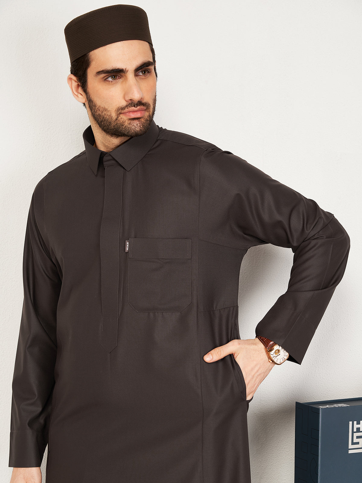 Man wearing a dark brown traditional outfit with a white background