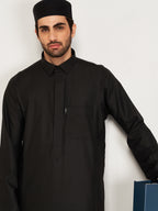 Man wearing a black traditional outfit with a white background