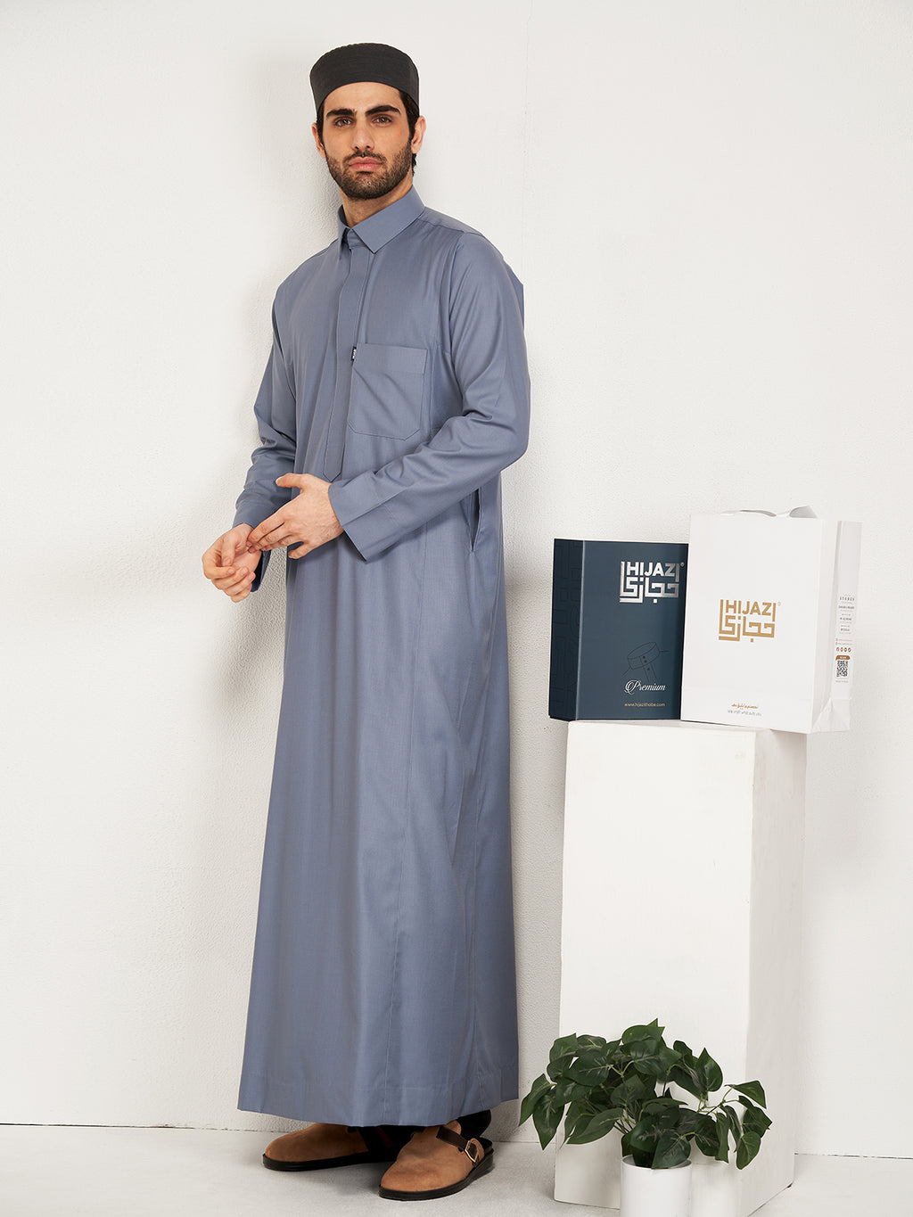 Man wearing a long grey thobe  with a white background