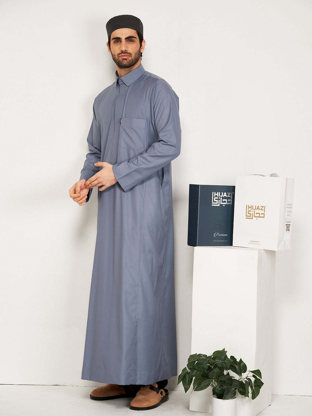 Man wearing a long grey thobe  with a white background