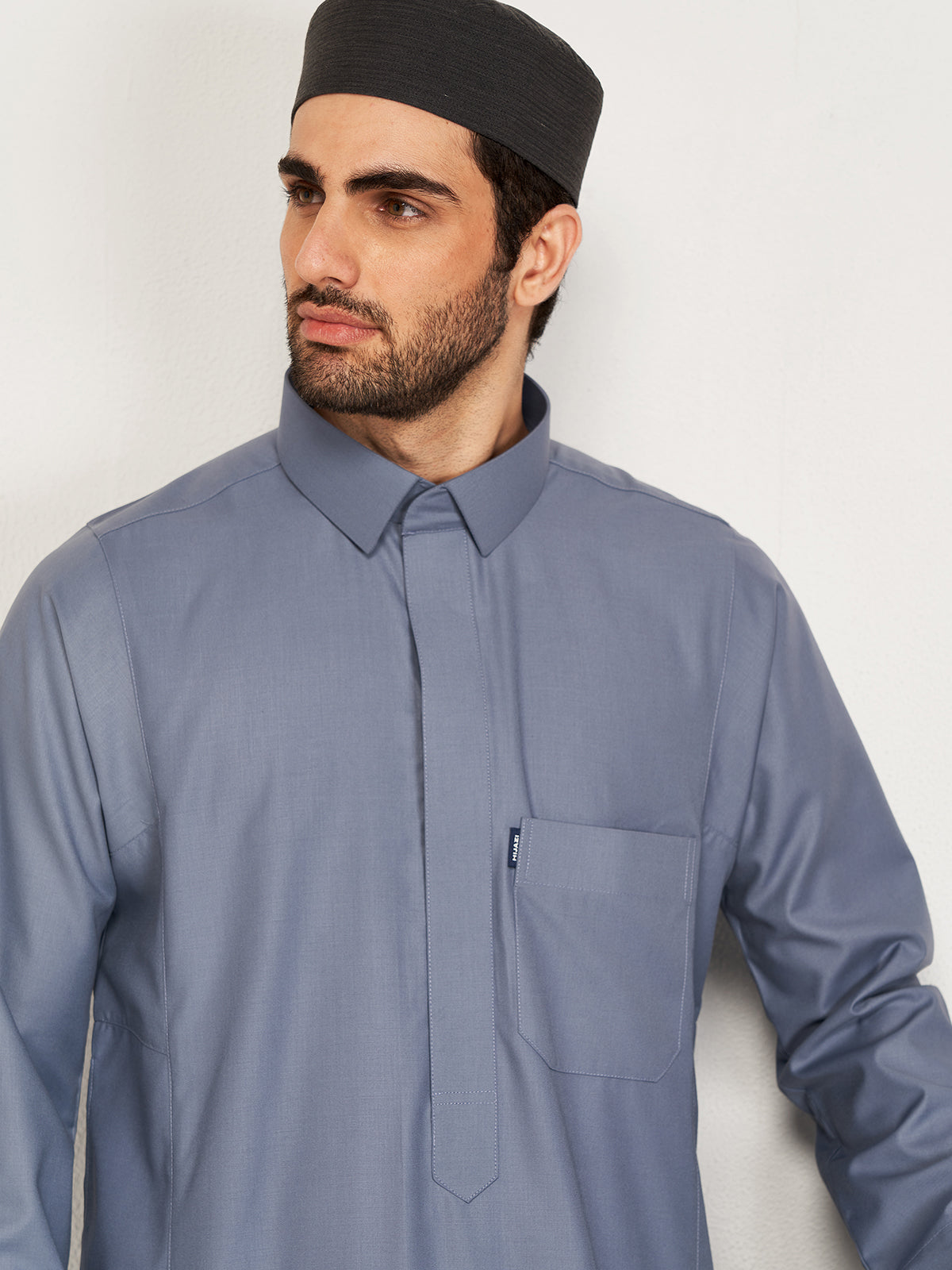 Man wearing a gray shirt and black cap against a white background