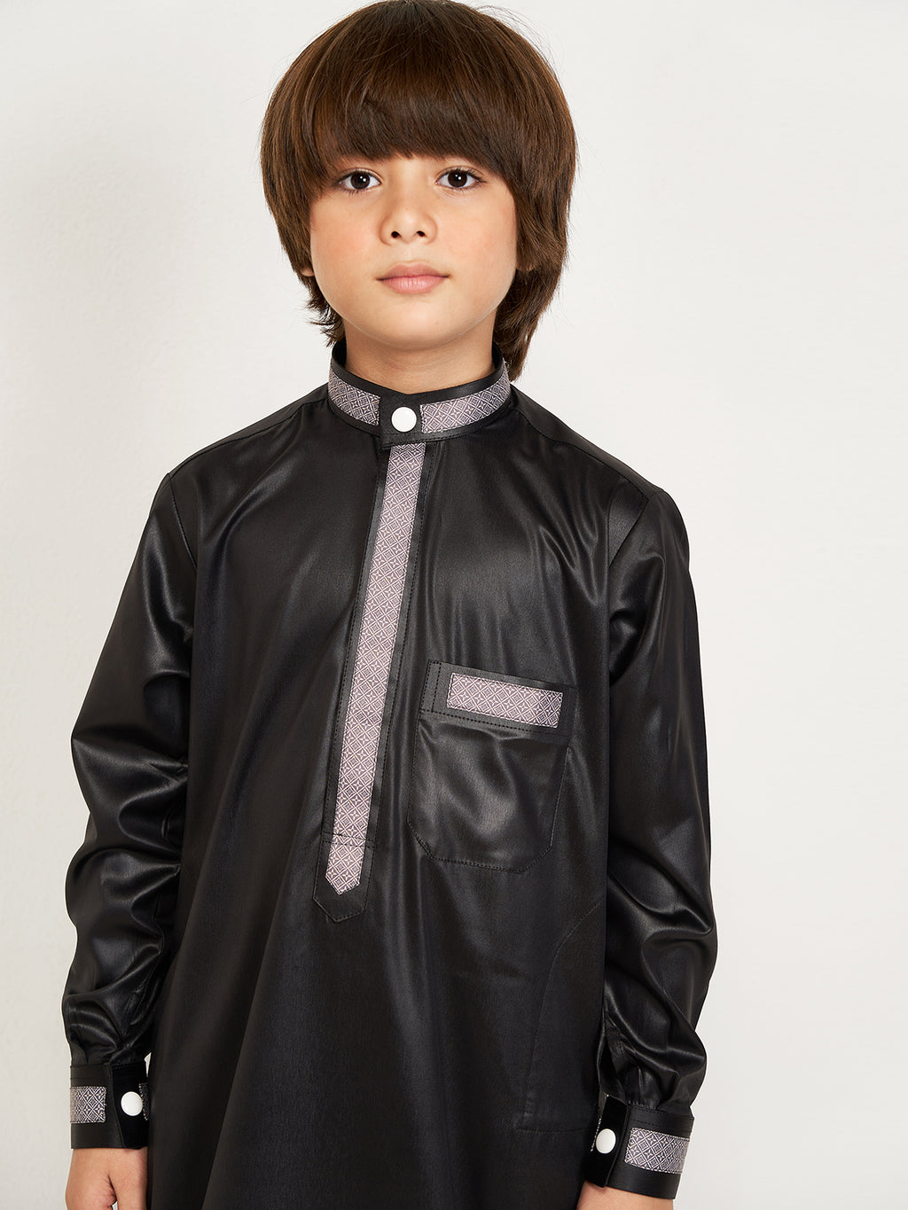 Child wearing a black traditional outfit with gray accents on a white background