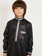 Child wearing a black traditional outfit with gray accents on a white background
